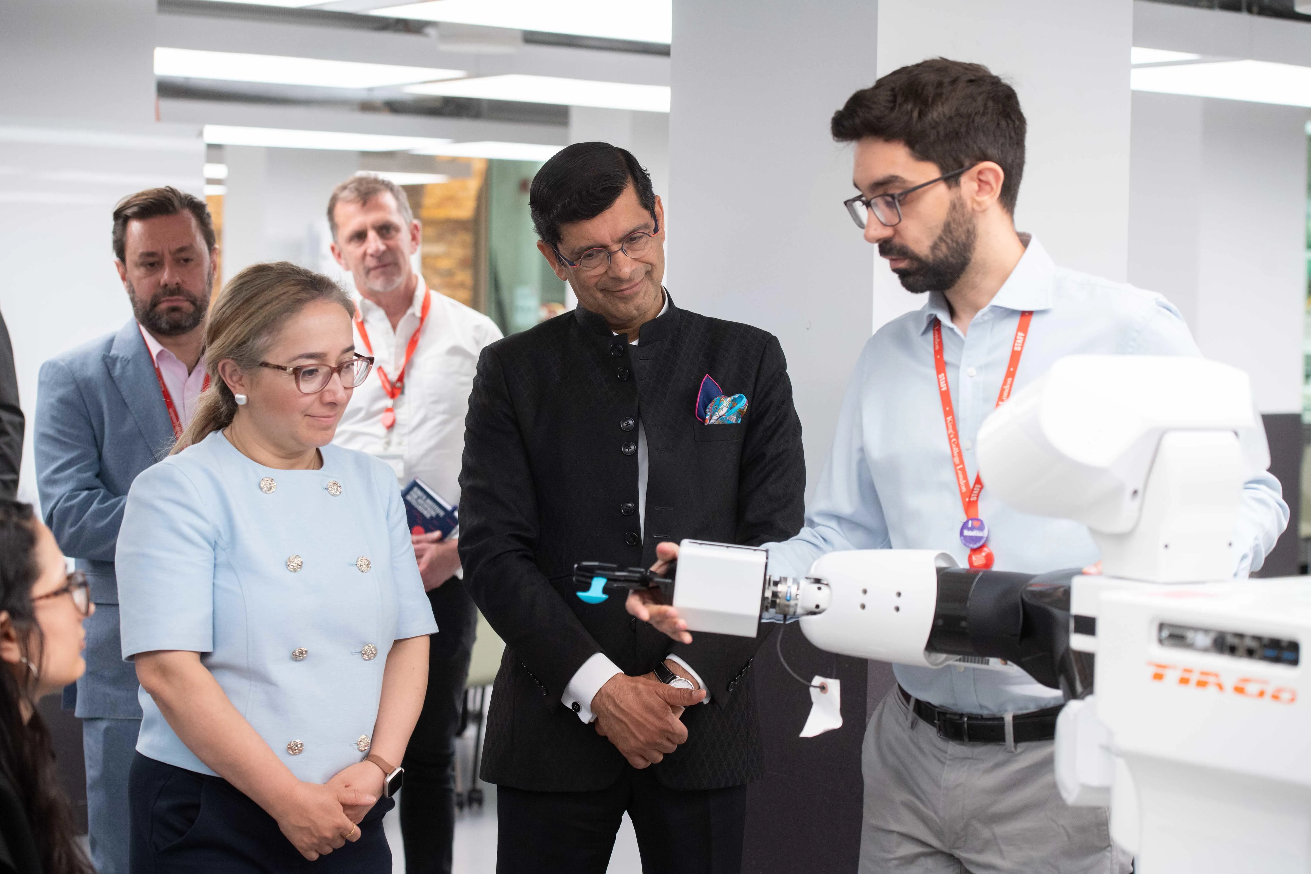Three people looking at a robot
