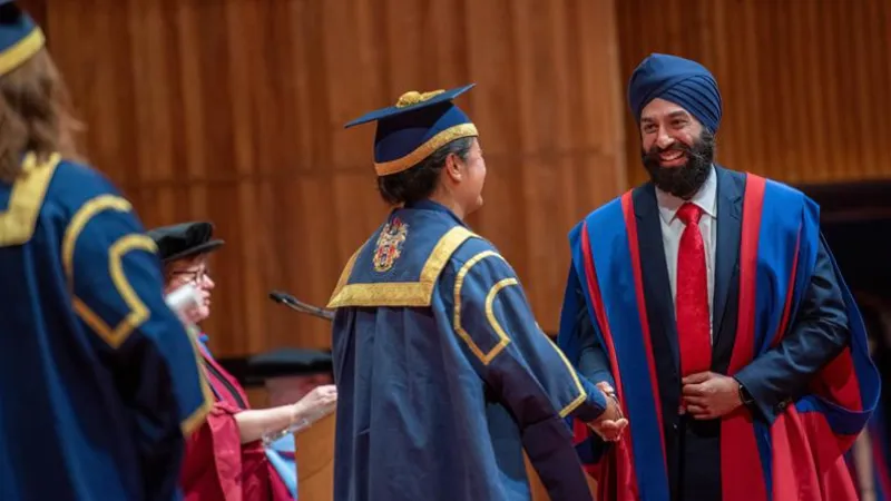 A King's student at their graduation shaking hands on the stage