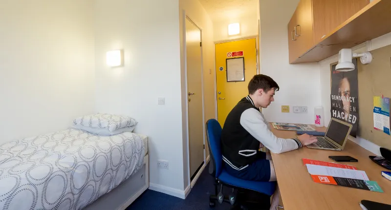 A man sitting at a desk and working on a laptop in a Great Dover Street apartment.