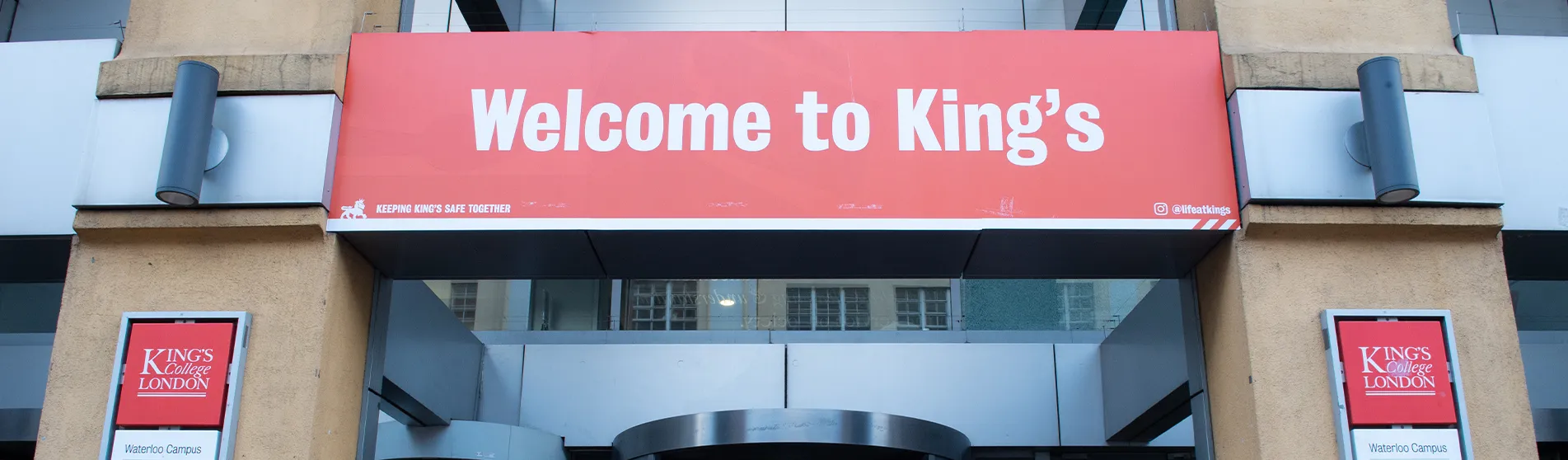 A red sign with 'welcome to King's' written on it above the entrance to a campus building
