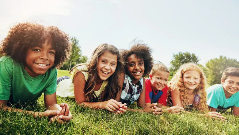 A group of children laying on grass and smiling 