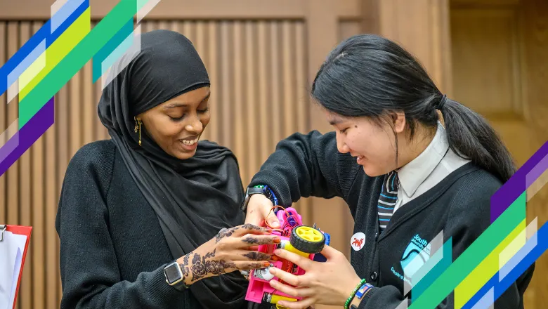 two girls fixing a small pink robot