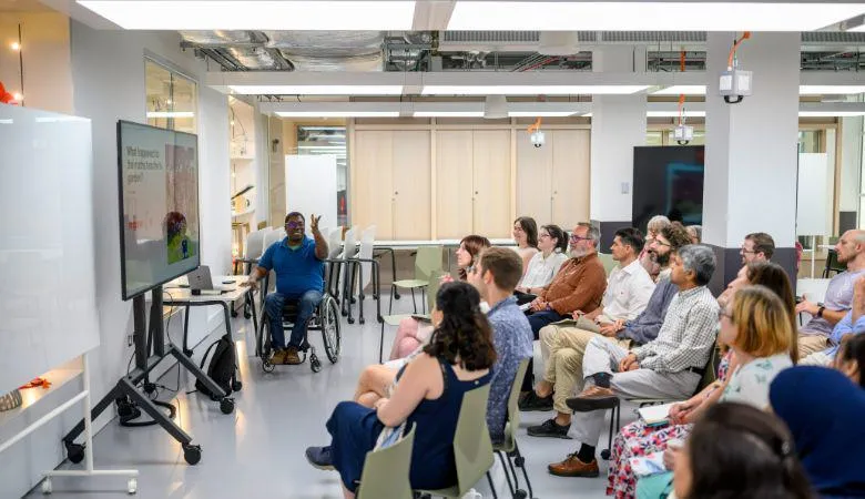 A lecturer in a wheelchair talks to a room of people