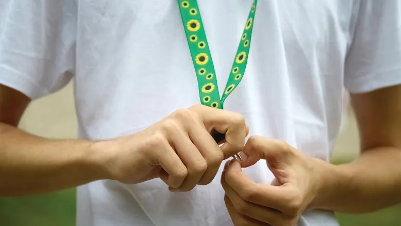 A close-up of a green lanyard with sunflowers on.