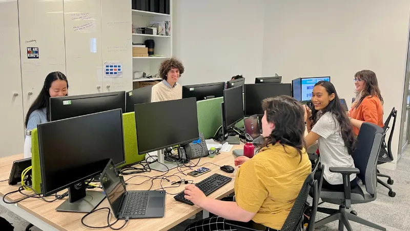 Jasmine, Henry, Alex, Dharshini and Ama sitting at their desks and chatting.